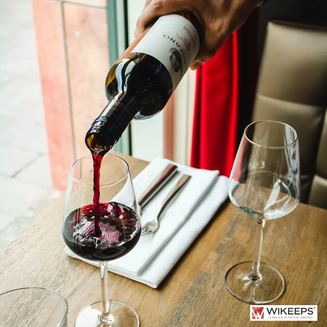 Un serveur est en train de servir du vin dans verre à vin