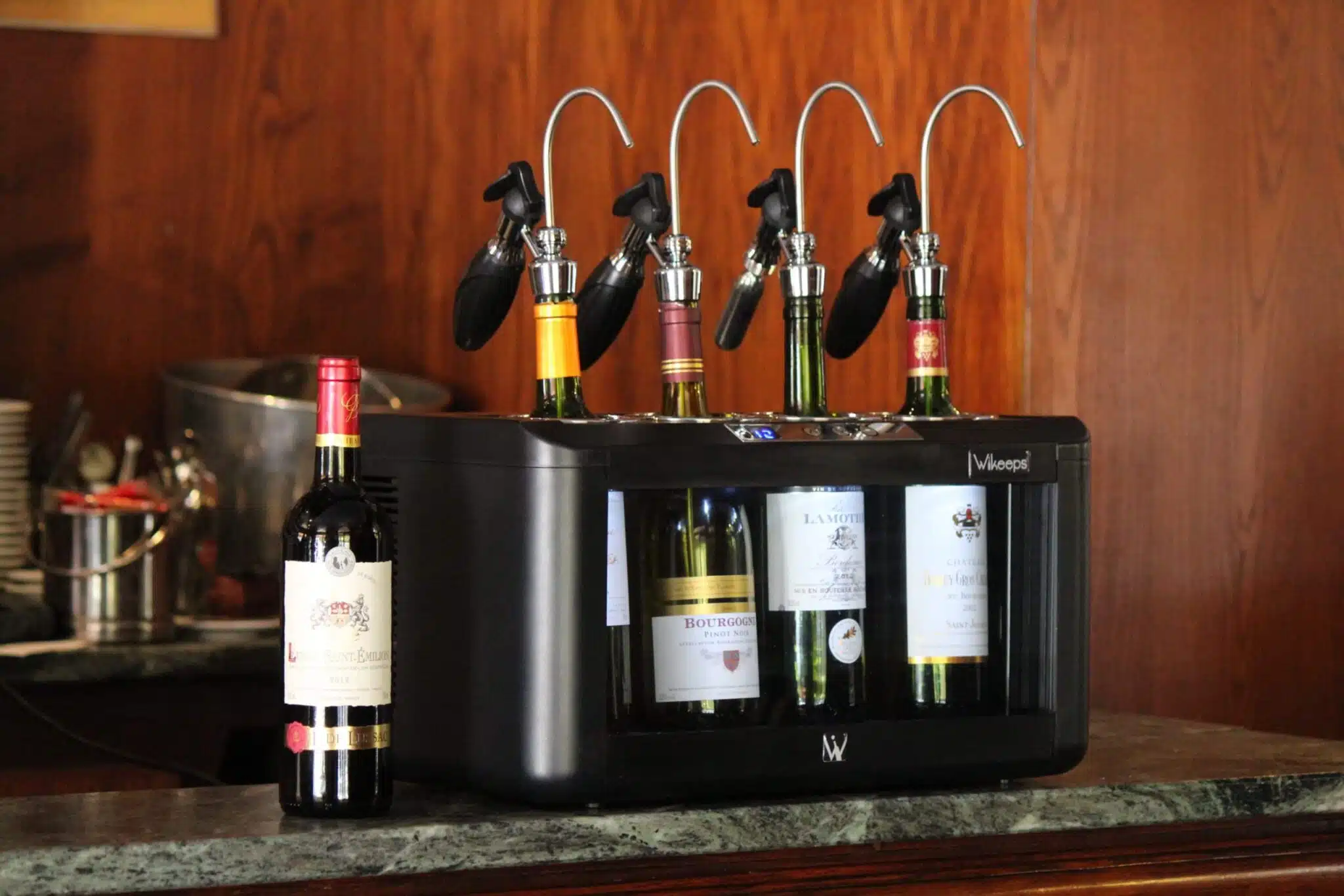 Wine bar: distributori con pistola Wikeeps su una macchina per spillare vini, con diverse bottiglie aperte. Wine bar: distributori con pistola Wikeeps su una macchina per spillare vini, con diverse bottiglie aperte.