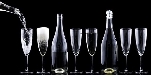 Plusieurs flûtes et bouteilles de champagne alignées, avec du champagne versé dans une coupe. Un élégant service de dégustation.